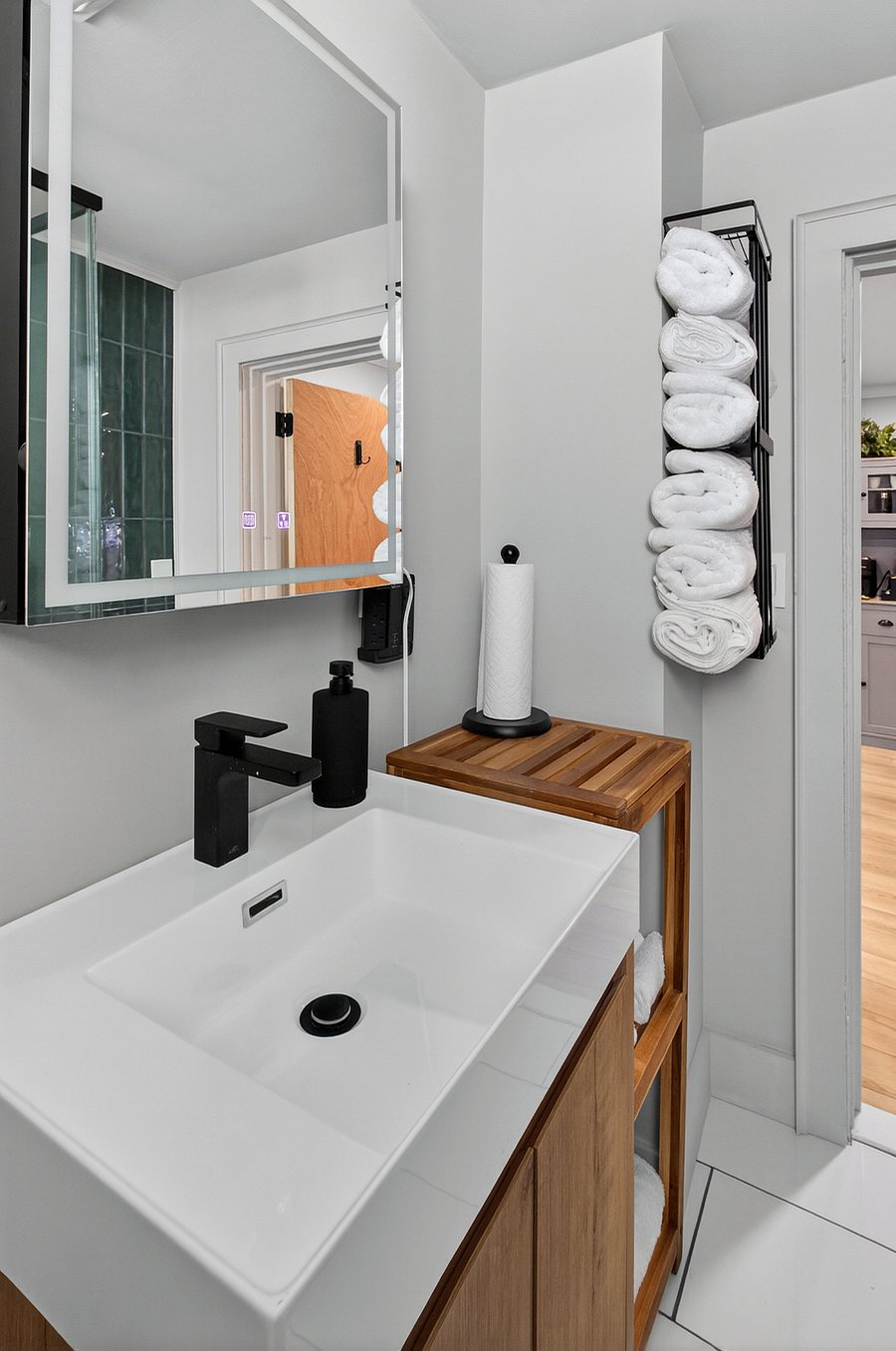 The bathroom includes shelving space for bath towels, washcloths, and a foot mat, providing organized and convenient storage.