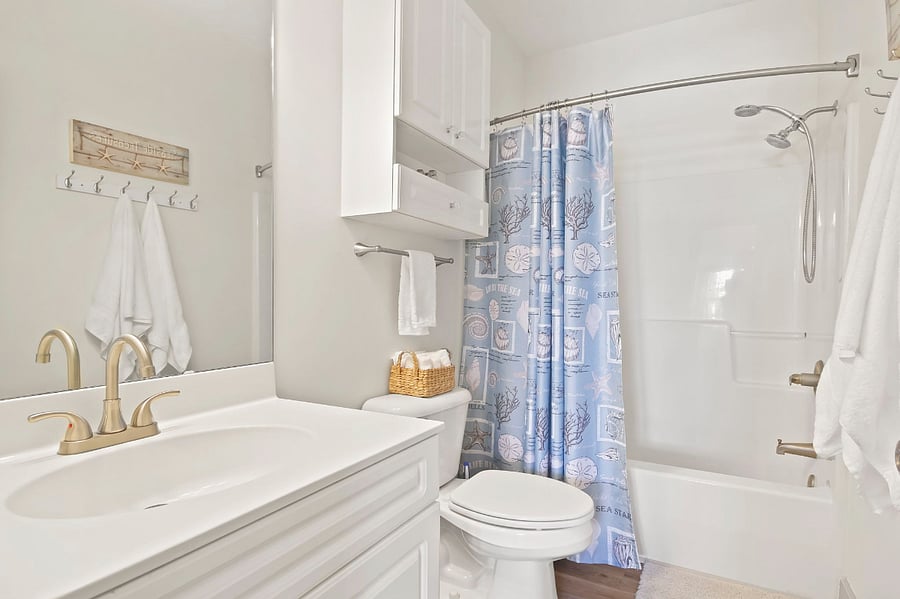 The main bathroom has a shower/tub combo, with storage space in the vanity and wall cabinet.