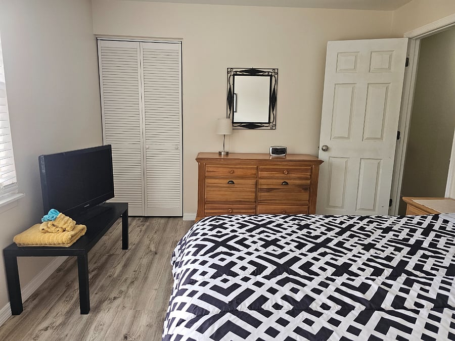 Master bedroom with California king sized bed and TV