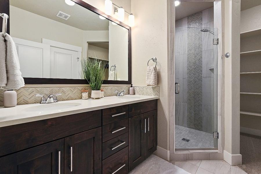 Spacious primary bathroom with double vanity, large walk-in shower with built-in bench, private toilet room, and generous closet.