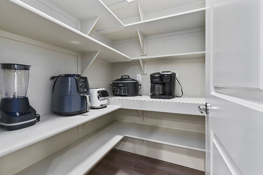 Spacious walk-in pantry offering ample storage and built-in outlets.