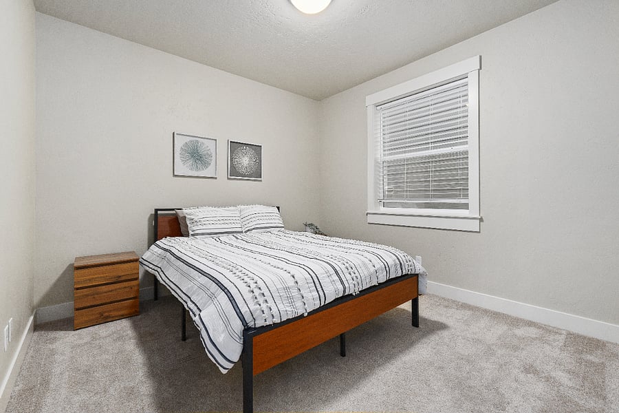 Downstairs bedroom featuring a queen-size bed, two three-drawer dressers, and a spacious closet with ample storage.