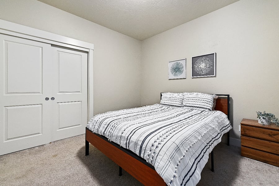 Downstairs bedroom featuring a queen-size bed, two three-drawer dressers, and a spacious closet with ample storage.