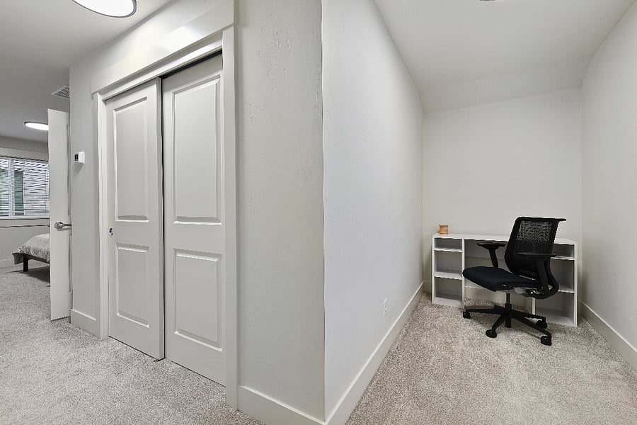 Small dedicated office area upstairs with desk and rolling chair, ideal for remote work.