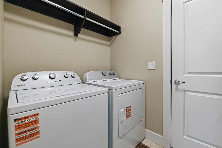 Separate laundry room featuring washer and dryer, storage cabinets, and sink.