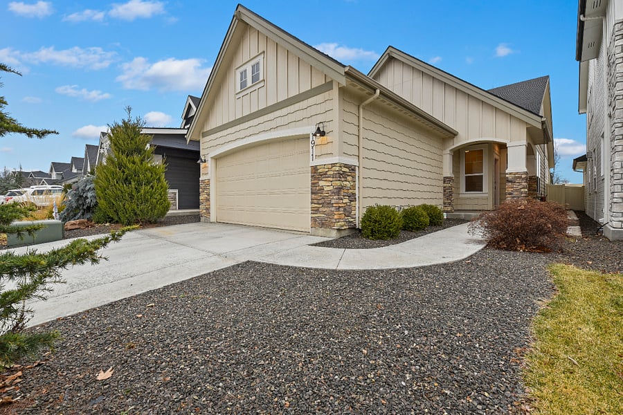 Home exterior with two-car garage, additional driveway parking for two vehicles, and low-maintenance front yard.