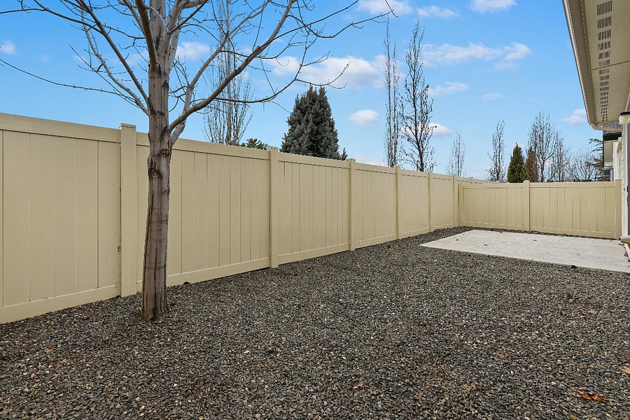 Low-maintenance backyard with vinyl fencing and river rock landscaping.