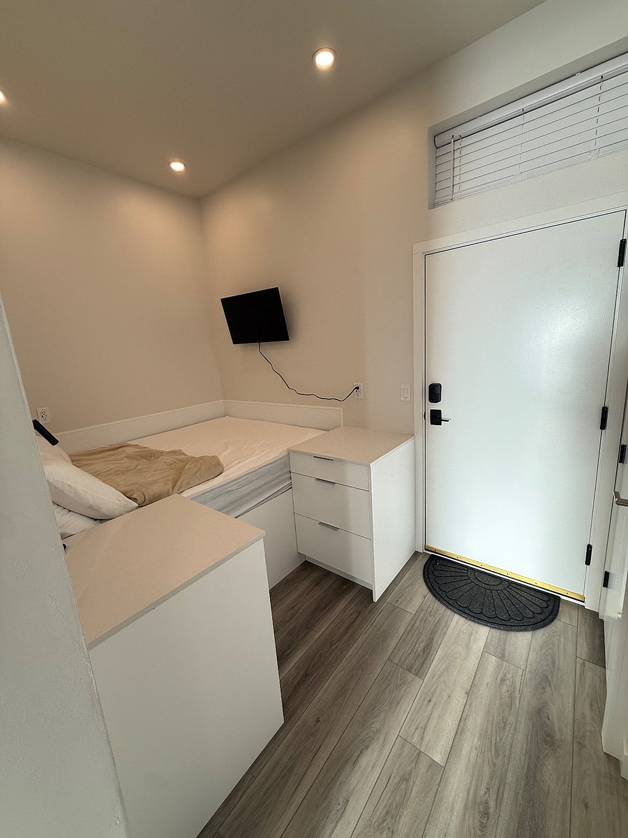 Queen-size bed in a thoughtfully designed sleeping area with smart TV, storage, and easy access to the private entrance.