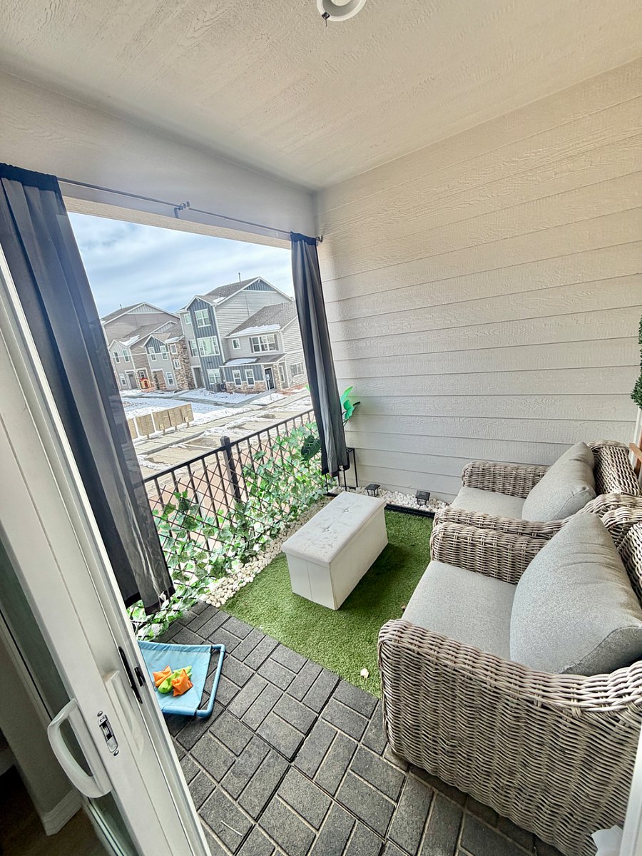The property features a nicely appointed patio with outdoor furniture and curtains, providing a functional and private space for outdoor seating and relaxation.
