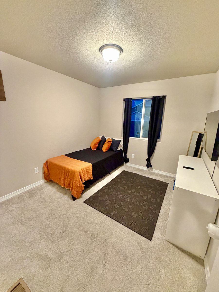 This second bedroom offers a clean and comfortable setup with an XL twin bed, a closet, tv, and a straightforward layout that provides a calm, uncluttered space.