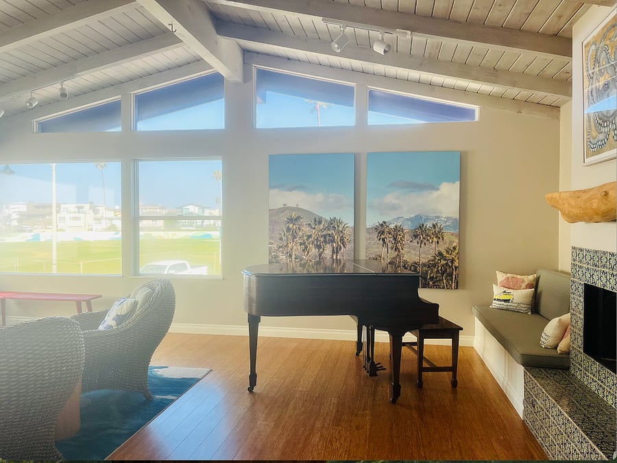 The living room has a gas fireplace, a baby grand piano, and views galore!