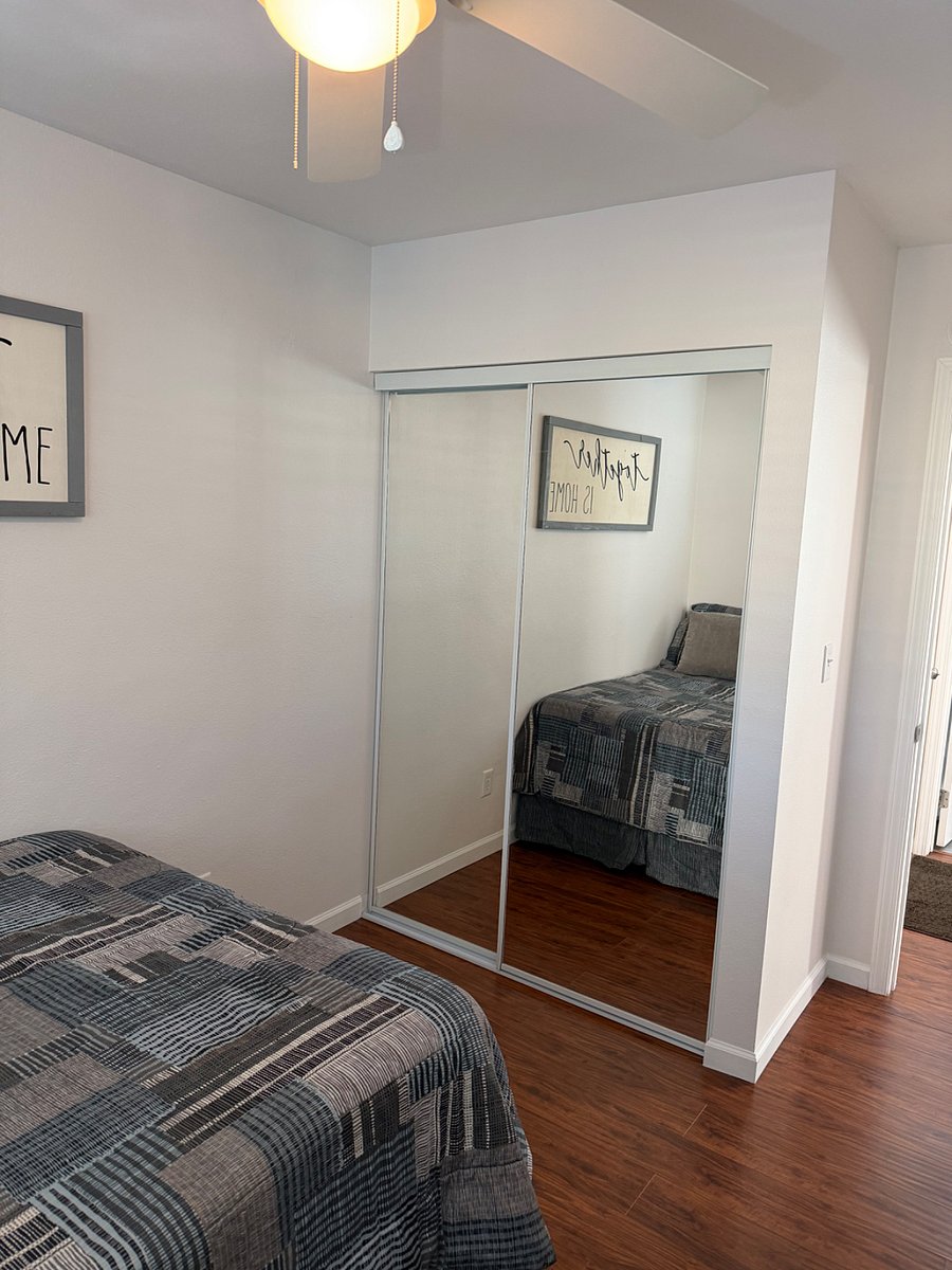Bedroom with sliding glass mirror closet, dresser drawers for storage, ottoman and a brand new full size bed