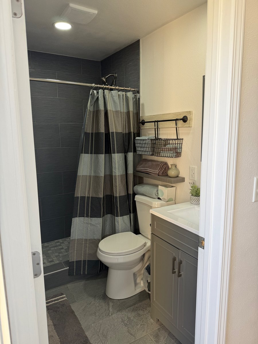 Bathroom with full walk in shower, toilet, mirror and vanity. 
