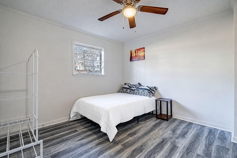 Bedroom with ceiling fan, large window, and space for a bed plus storage; durable flooring for easy upkeep.