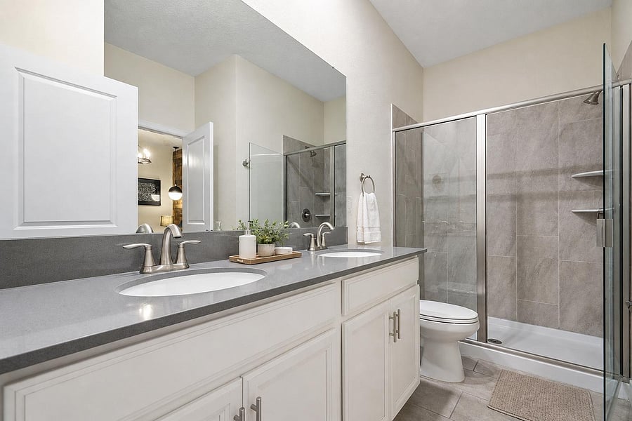 Spacious bathroom with double-sink vanity, ample counter space, and a glass-enclosed shower with tile surround.