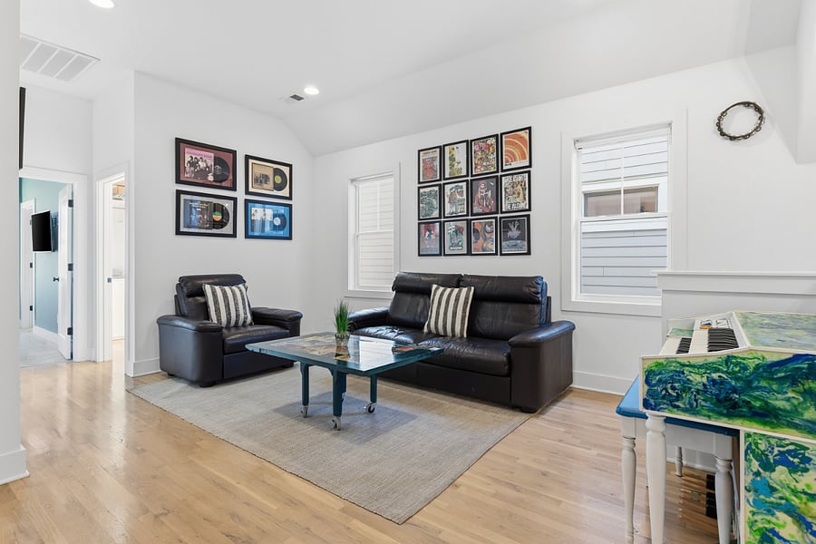 Second living room area on the second floor with comfortable seating, smart TV, piano and guitars.
