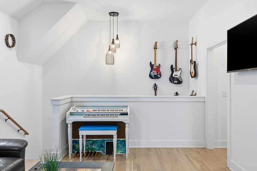 Second living room area on the second floor with comfortable seating, smart TV, piano and guitars.
