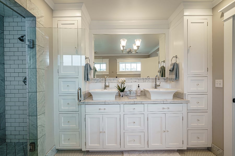Spa-like private main suite bathroom with double sinks, marble counters, dual-head shower, tons of storage and a radiant-heated tile floor