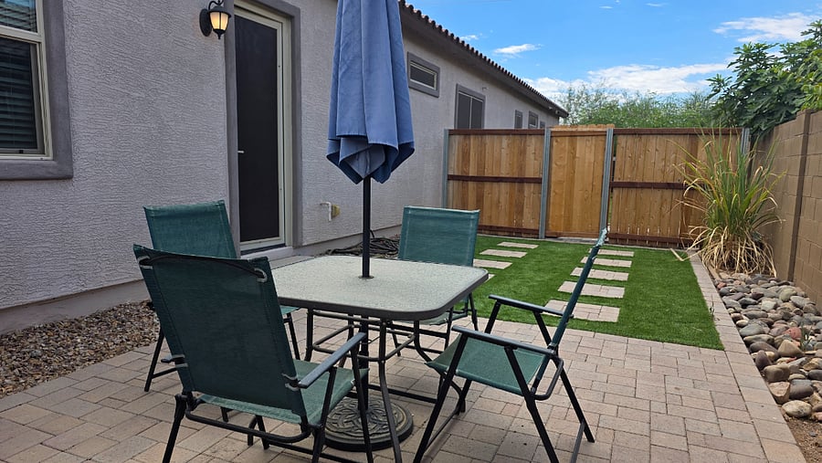 Manicured private fenced in yard with table and umbrella