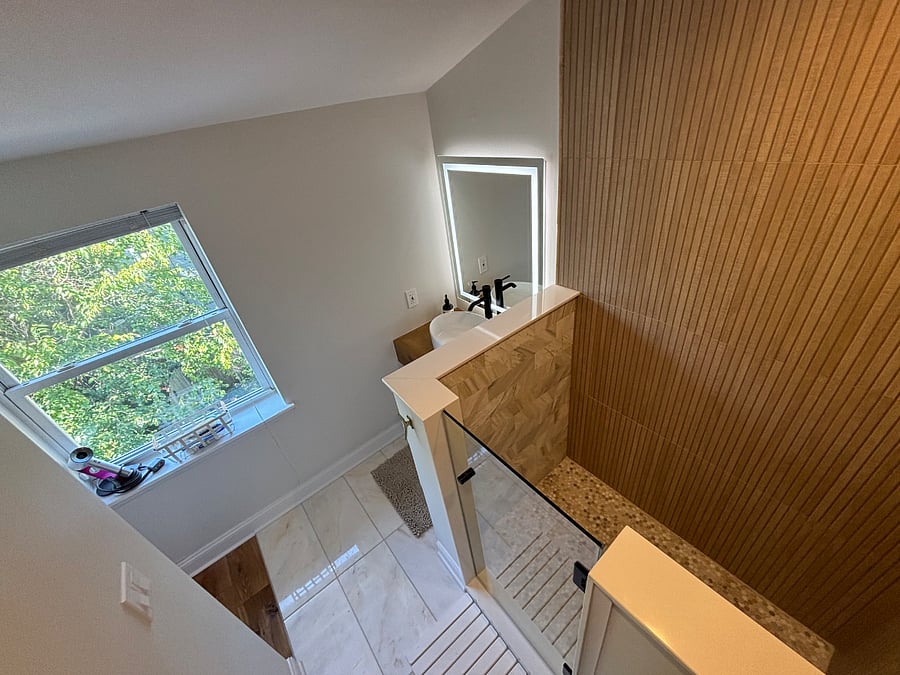 Third floor bathroom, new as of 2024; spa like design with marble tiles, wood finishes, open/natural light, and rain shower