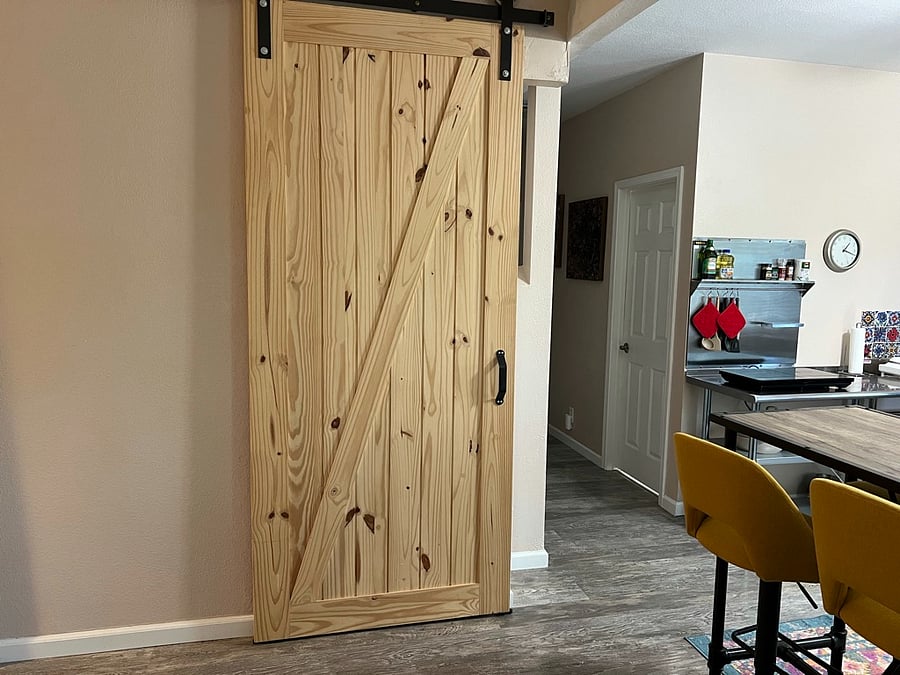 Barn door to stairs to owner's home and shared laundry room, kitchenette to the right