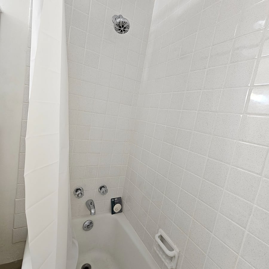 Full size bath & shower with new bath mat, shower curtain,and shower caddy.