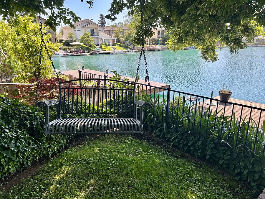 Beautiful backyard on the lake with covered patio, bench swing, and dock