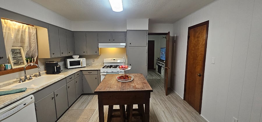 Large kitchen with gas range, cast iron sink, tons of storage, closet pantry, plus island on casters with 4 stools stored underneath.