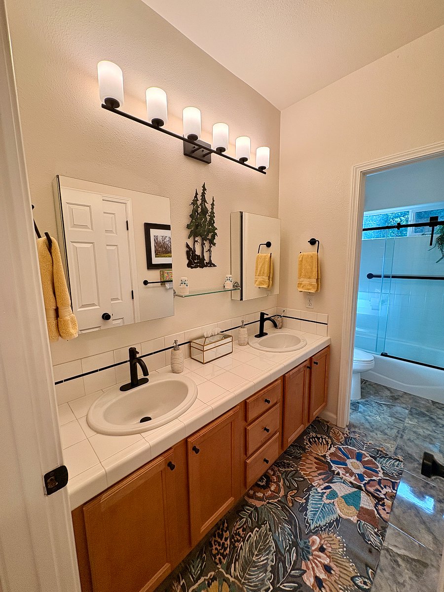 Private bath with dual sinks and mirrored vanity cabinets.