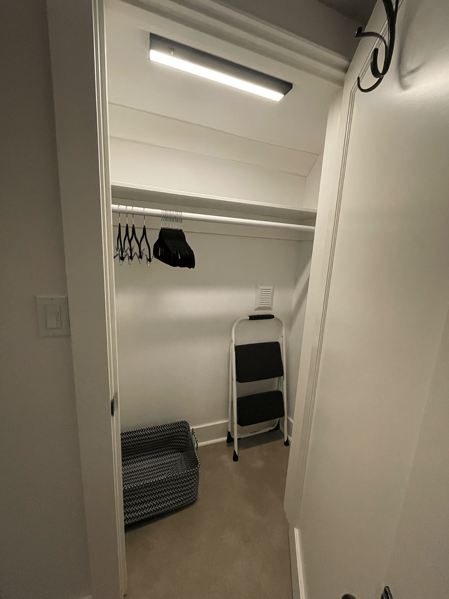 Bedroom closet with hangers, laundry basket and step stool.