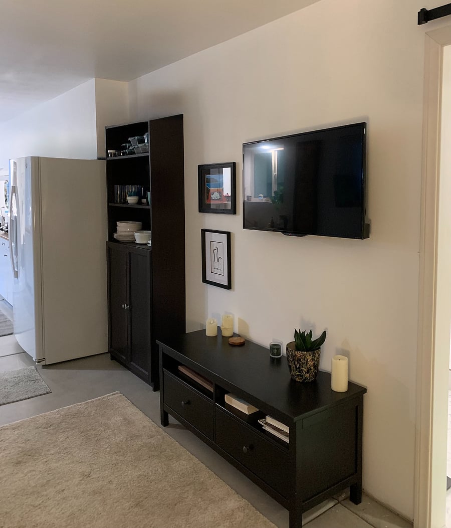 Wall-mounted tv across from comfy couch with storage cabinet below and more cabinet storage along the same wall. 