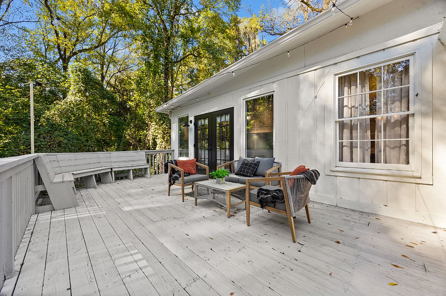 Patio with lounge area, string lights and gate. Stairs are leading down to a fully fenced in backyard.