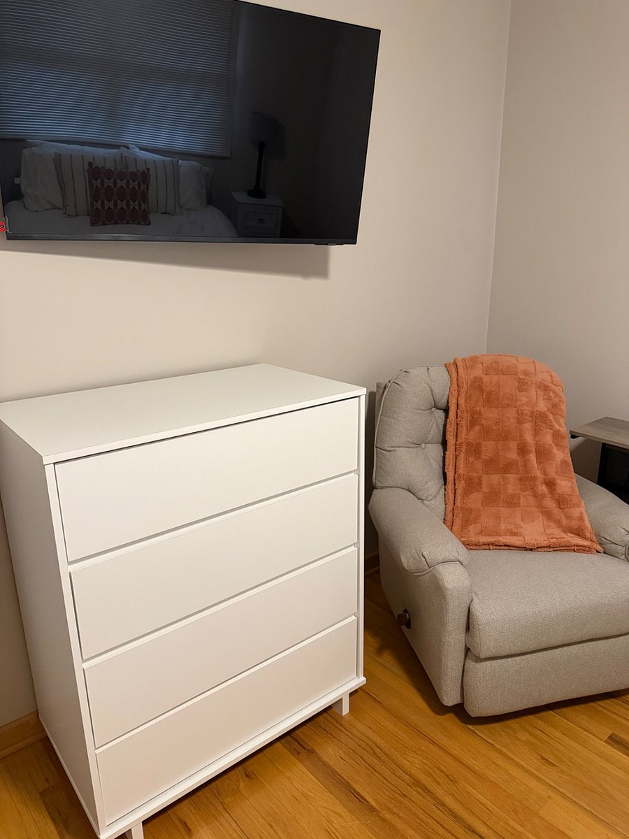 Dresser and comfy recliner with side table for electronics.
