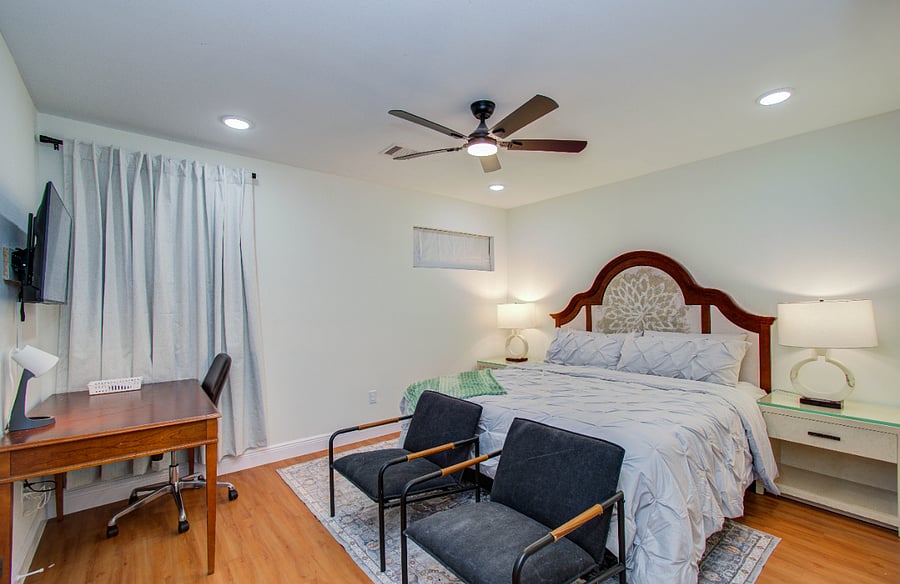 Primary bedroom with king bed, Smart TV accent chairs workspace and a closet