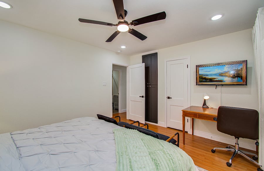 Primary bedroom with king bed, Smart TV accent chairs and a workspace