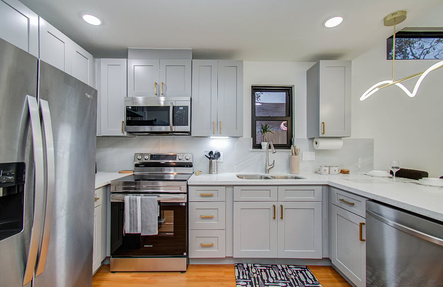 Kitchen with shaker cabinets and quartz countertop, electric stove, microwave and dishwasher