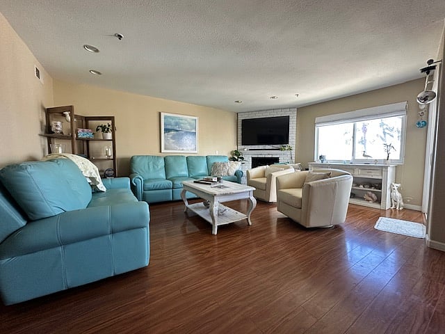 Large living area with leather couches and swivel chairs, big screen TV and fireplace.