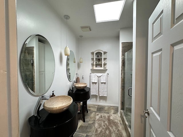 Double sinks with drawers and mirrors and a storage closet next to showerSp