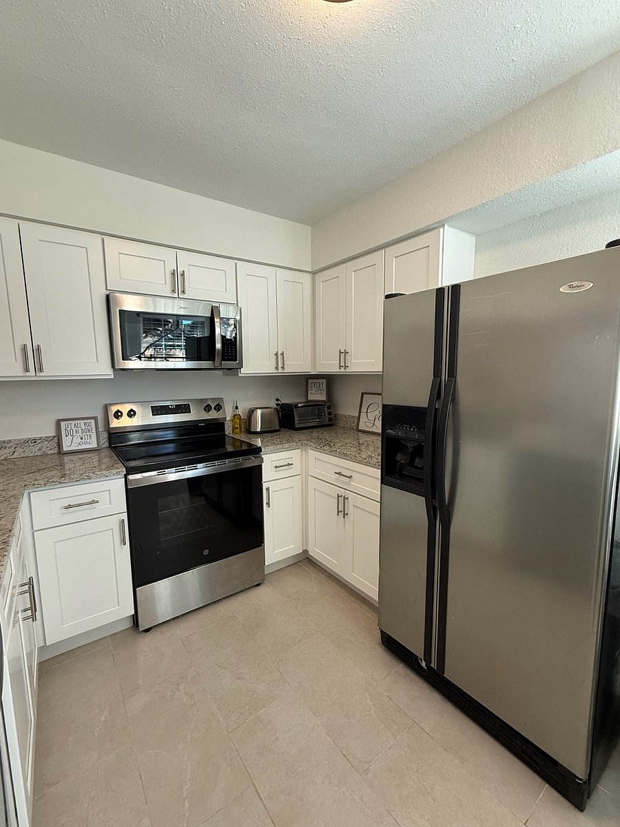 Kitchen with sink, open countertop to dining area, full size refrigerator and freezer, 4 burner stovetop, full sized oven, microwave, countertop toaster oven