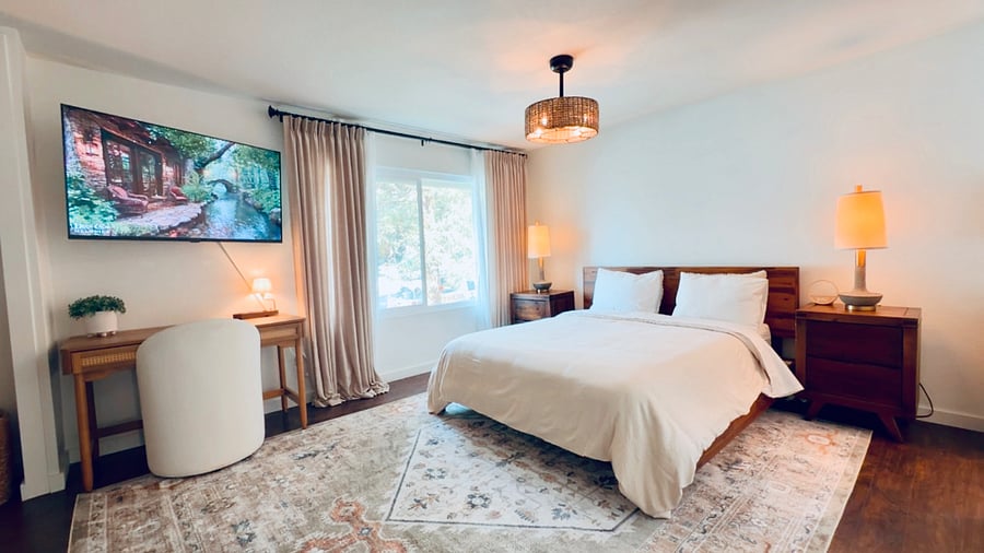 Spacious master bedroom featuring a comfortable bed, smart TV, and dedicated workspace.