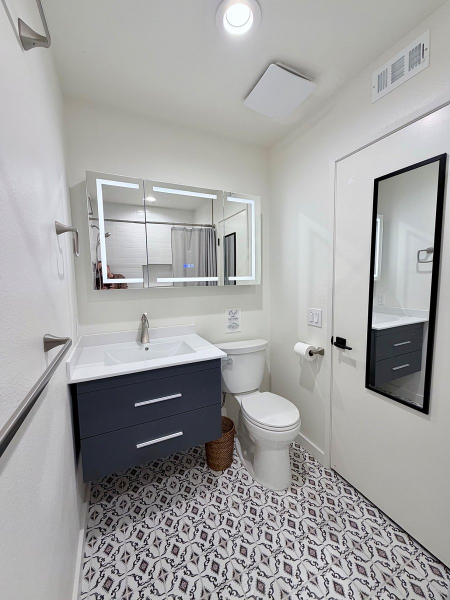 Updated full bathroom with modern vanity, illuminated mirror, and clean contemporary finishes.