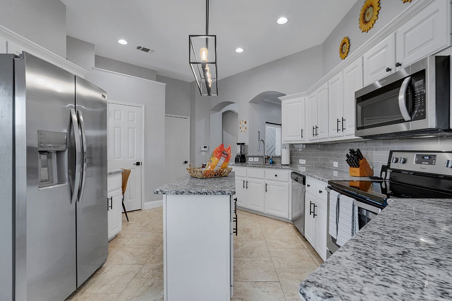 Large kitchen with prep island, oven, stove, dishwasher, microwave, and small appliances: blender, toaster, and coffee service.