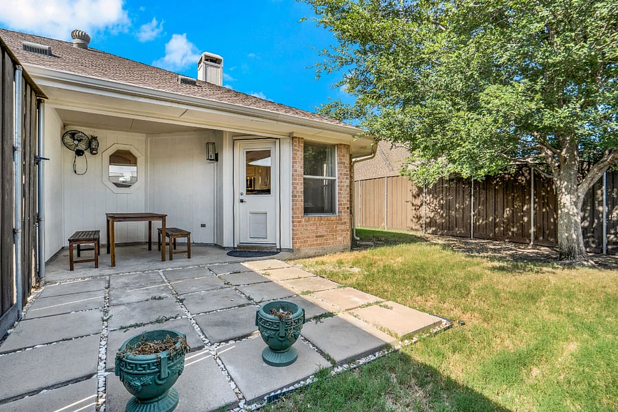 Covered back patio off the kitchen with dining set in backyard