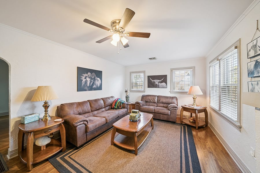 The spacious living room is designed for comfort and relaxation, featuring a comfortable sofa and loveseat, side tables, and a coffee table. Guests can unwind while watching the Smart TV or browse the collection of books featuring Tulsa's history, attractions, restaurants, and local points of interest to help plan their stay.