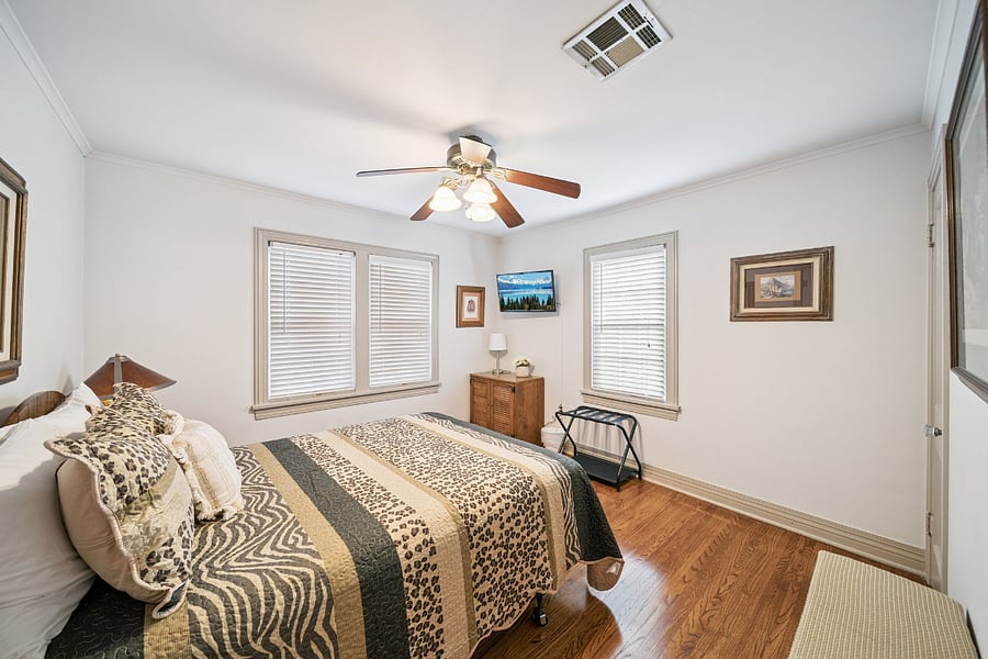 A second view of Bedroom #1 showcases the spacious layout and thoughtful amenities. In addition to the queen-size bed, ceiling fan, Smart TV, and closet, the room also includes a luggage rack to make unpacking and extended stays more convenient.