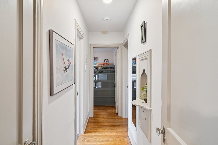 The hallway highlights the rich history and original character of this 1920s home. A beautifully preserved original telephone cabinet remains in place, adding a unique touch of vintage charm. The home also features a whole-house attic fan, perfect for bringing in fresh air during the pleasant spring and fall seasons.
This hallway connects Bedrooms #2 and #3 to the main bathroom and dining room, providing a convenient layout while showcasing the home's timeless architecture and history.
