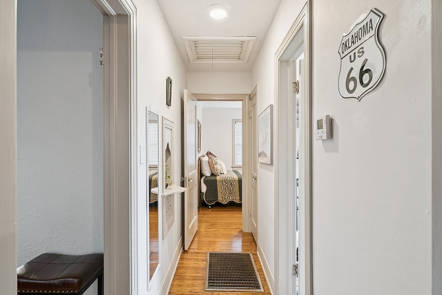 This view from Bedroom #2 looks down the hallway toward Bedroom #1, illustrating the home's thoughtful floor plan and easy flow between the bedrooms, main bathroom, dining room, and living room. The hallway also showcases the home's original architectural details, adding to its historic charm and inviting atmosphere.