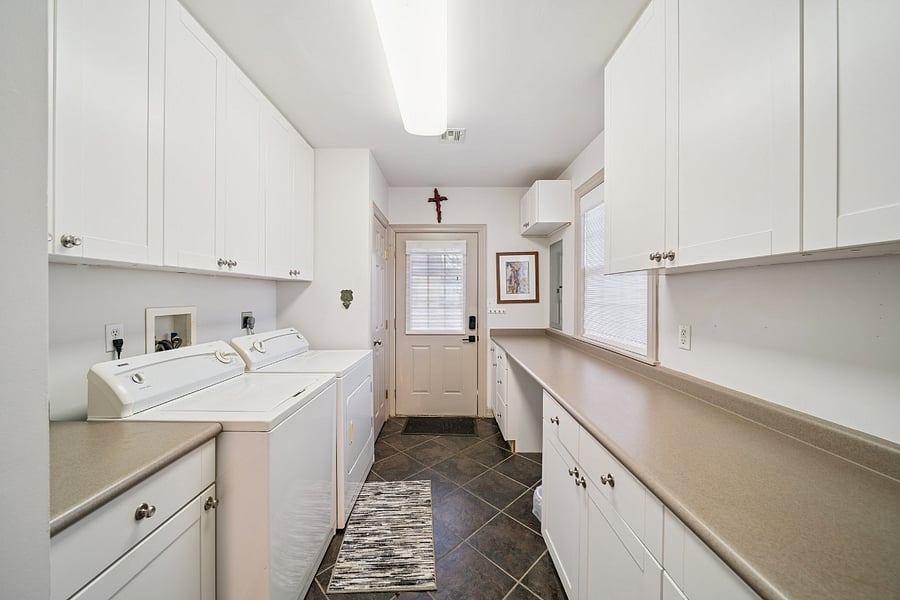 A second view of the laundry room highlights the full-size washer and dryer along with the large countertops, providing plenty of space for folding clothes, organizing laundry, or storing personal items during your stay. This spacious utility room is designed to make extended stays comfortable and convenient.