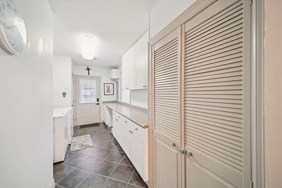 The spacious laundry room is conveniently located just off the kitchen with easy access to the back door. It features a full-size washer and dryer, making it ideal for extended stays. There's plenty of room for sorting and folding laundry, along with additional space for storing cleaning supplies and other household essentials.