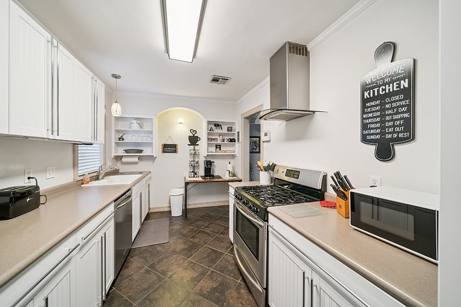 A second view of the updated kitchen showcases the blend of modern updates and historic character. While the kitchen has been thoughtfully renovated, some of the original open shelving has been preserved to reflect the home's 1920s charm and history. These unique details add warmth and personality, creating a welcoming space that honors the home's past while providing the conveniences of today.